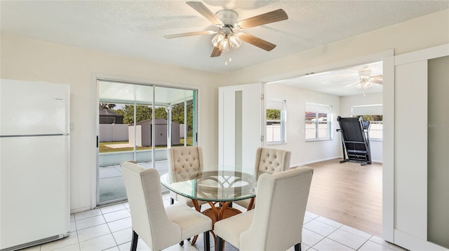 dining room featuring a textured ceiling, light tile patterned flooring, and ceiling fan