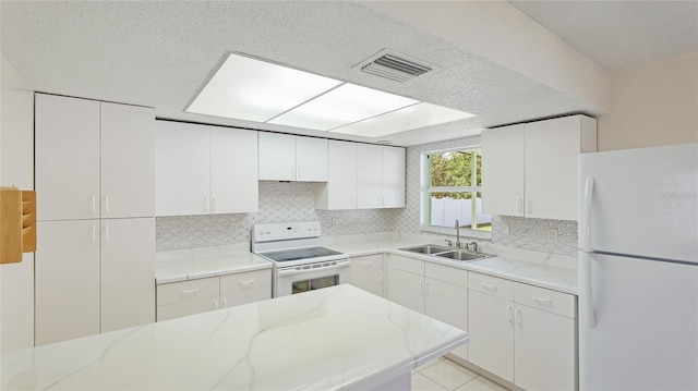 kitchen with white appliances, visible vents, a sink, white cabinets, and tasteful backsplash