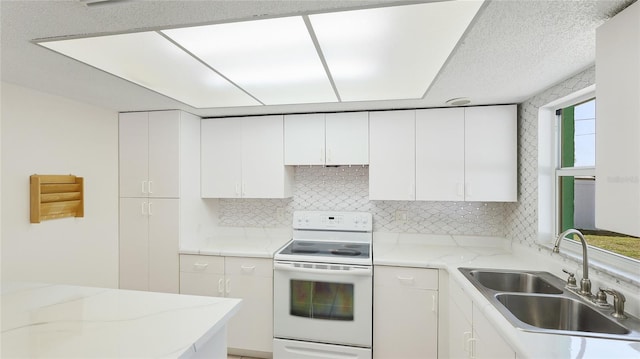 kitchen with decorative backsplash, white cabinets, electric stove, and a sink