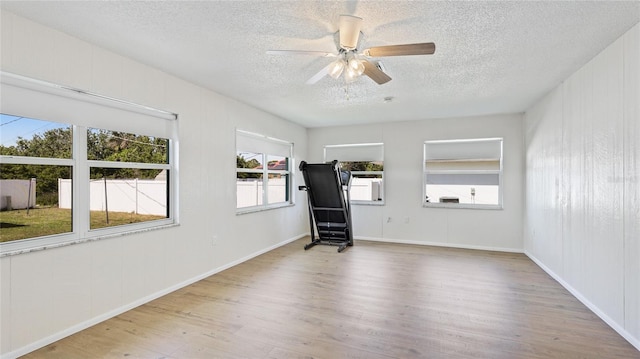 empty room featuring ceiling fan, baseboards, a textured ceiling, and wood finished floors