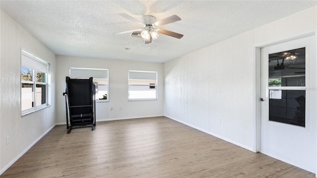 spare room featuring wood finished floors, baseboards, visible vents, ceiling fan, and a textured ceiling