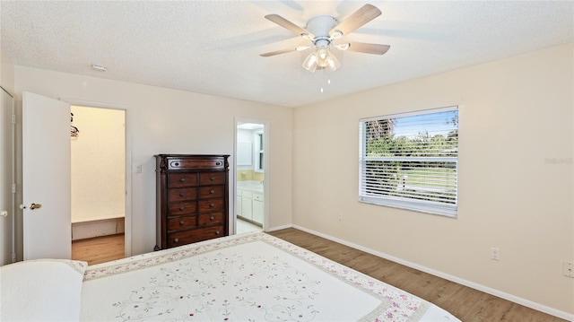 bedroom featuring a textured ceiling, ensuite bath, wood finished floors, baseboards, and ceiling fan