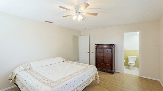 bedroom with visible vents, a ceiling fan, a textured ceiling, ensuite bath, and light wood-style floors