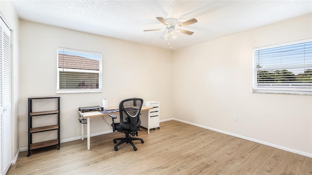 office area with a wealth of natural light, a textured ceiling, wood finished floors, and a ceiling fan