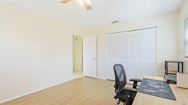 office with light wood finished floors, visible vents, baseboards, and a ceiling fan