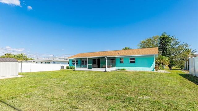 back of house with an outbuilding, a lawn, fence, and a sunroom