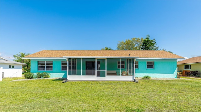 rear view of house with a yard, a sunroom, and stucco siding