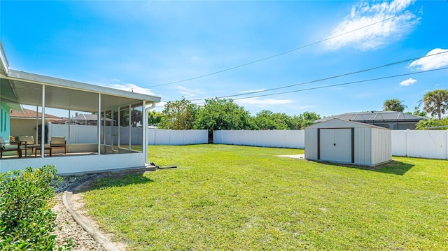 view of yard with a storage shed, an outdoor structure, a fenced backyard, and a sunroom