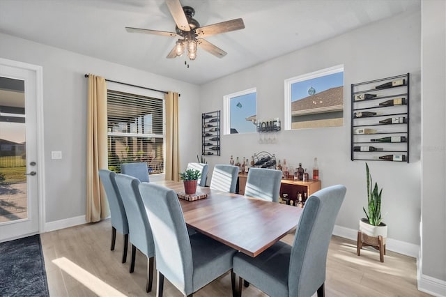 dining area featuring a ceiling fan, light wood-style floors, baseboards, and a wealth of natural light