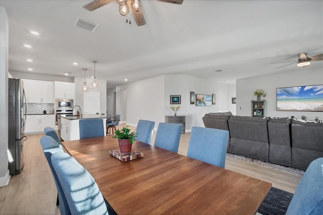 dining space with visible vents, light wood-style floors, and a ceiling fan