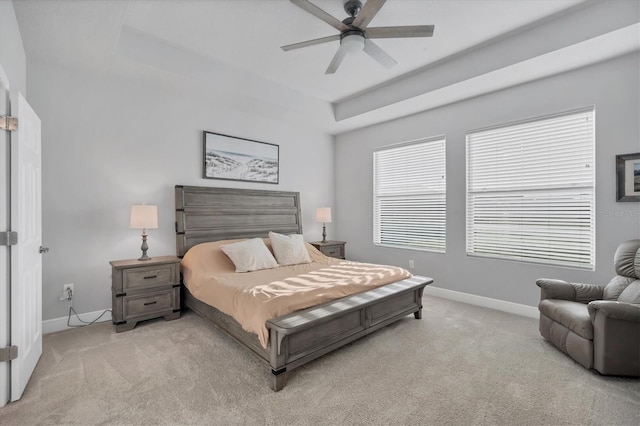 bedroom featuring light carpet, a tray ceiling, and baseboards