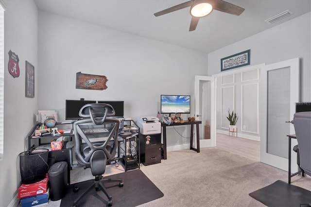 carpeted office with visible vents, baseboards, and a ceiling fan