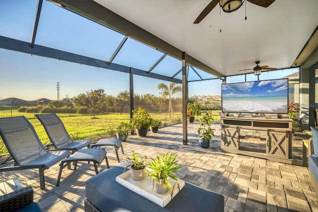 view of patio with glass enclosure, ceiling fan, and fence