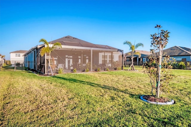 rear view of house featuring a lawn, glass enclosure, and fence