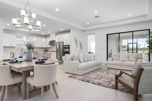 living room with visible vents, recessed lighting, a raised ceiling, and an inviting chandelier