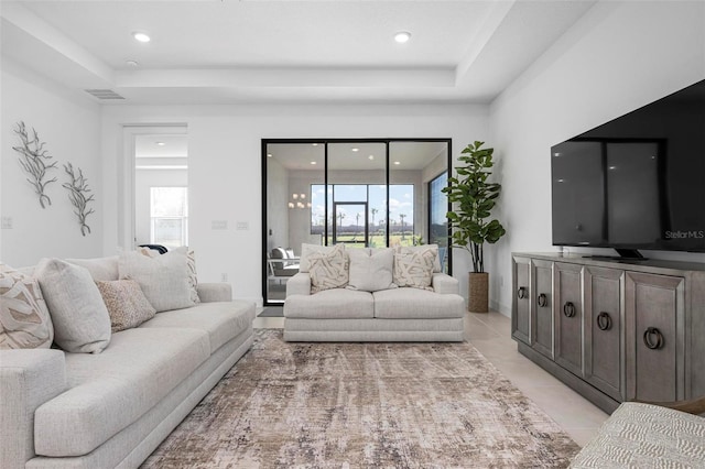 living room featuring light tile patterned floors, visible vents, recessed lighting, and a tray ceiling