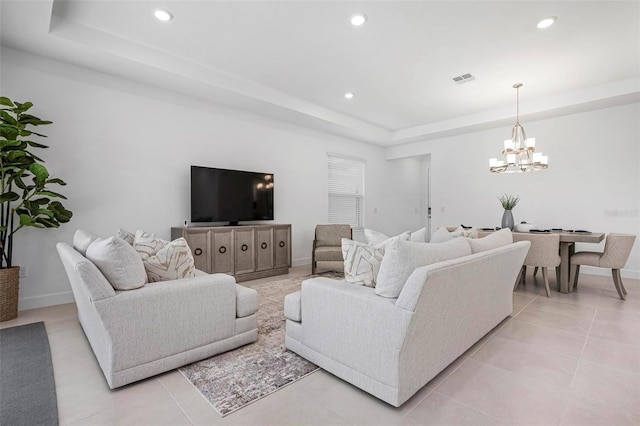 living area with visible vents, baseboards, a tray ceiling, recessed lighting, and a notable chandelier