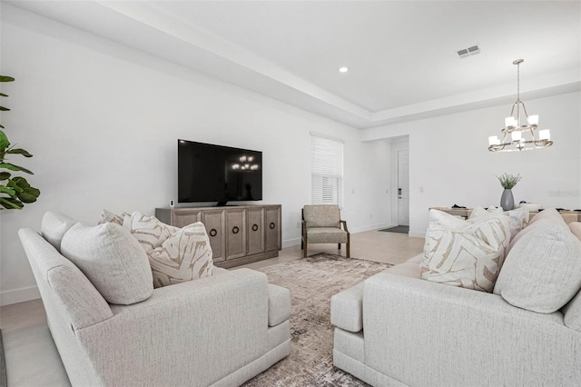 living area with visible vents, a notable chandelier, a raised ceiling, recessed lighting, and baseboards