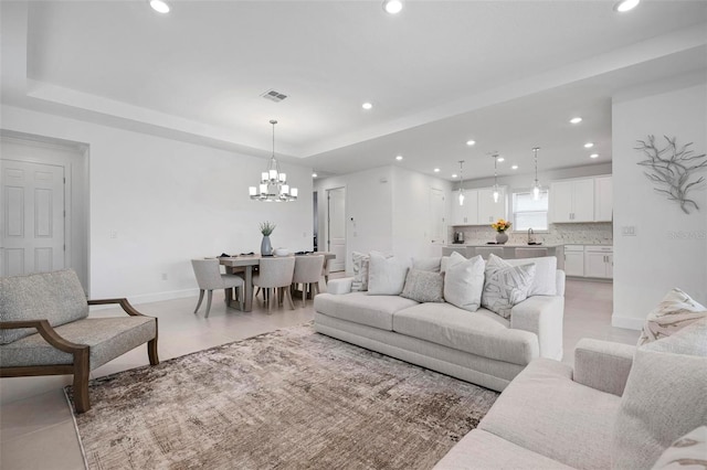 living area with visible vents, a tray ceiling, recessed lighting, an inviting chandelier, and light tile patterned flooring