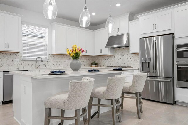 kitchen with light countertops, a center island, under cabinet range hood, and stainless steel appliances