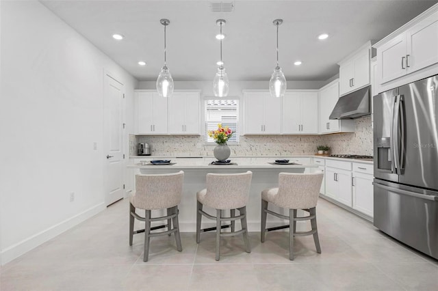 kitchen featuring visible vents, backsplash, under cabinet range hood, a breakfast bar area, and stainless steel appliances