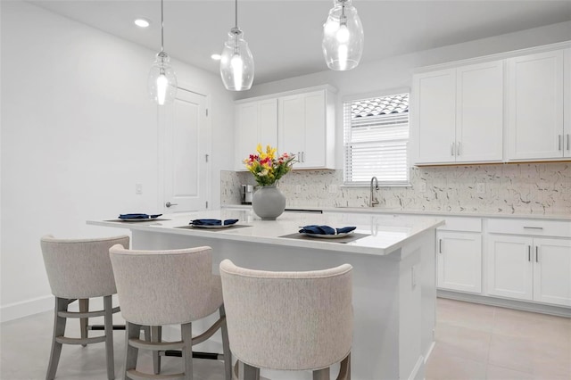 kitchen with a sink, tasteful backsplash, a kitchen island, white cabinetry, and light countertops