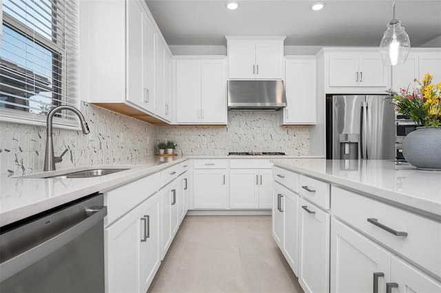 kitchen featuring light tile patterned flooring, a sink, decorative backsplash, under cabinet range hood, and appliances with stainless steel finishes