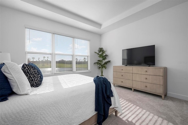 bedroom featuring baseboards, light colored carpet, and a raised ceiling