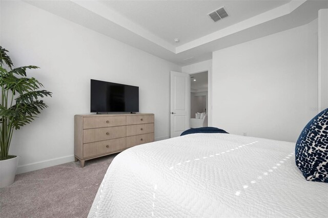 carpeted bedroom featuring visible vents, a raised ceiling, and baseboards