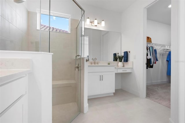 full bath featuring a stall shower, vanity, and a walk in closet