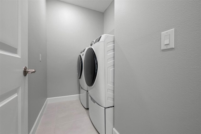 clothes washing area with washer and clothes dryer, laundry area, baseboards, and light tile patterned floors