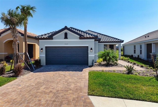 mediterranean / spanish-style house with stucco siding, decorative driveway, an attached garage, and a tiled roof