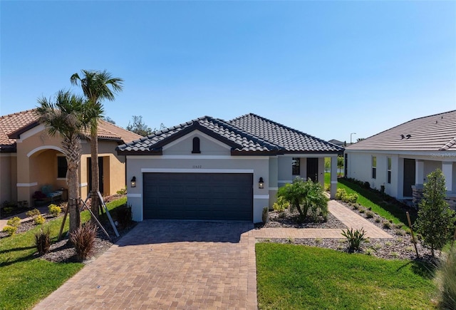 view of front facade featuring a tiled roof, a garage, decorative driveway, and stucco siding