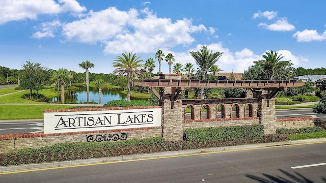 community sign featuring a water view and uncovered parking