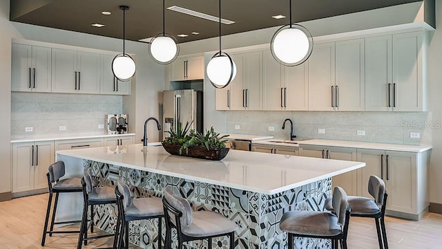 kitchen featuring light wood-style floors, high end fridge, a breakfast bar area, and light countertops