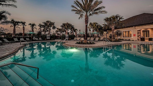 pool at dusk featuring a community pool and a patio area