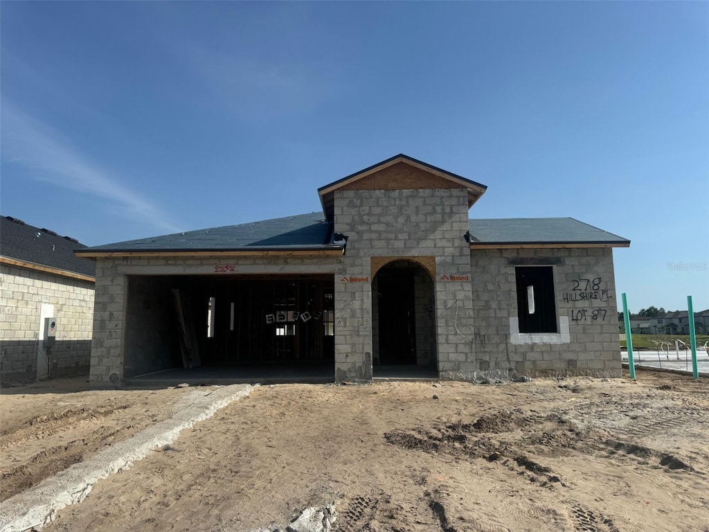 property in mid-construction featuring a garage, dirt driveway, and stone siding