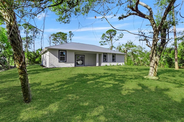 exterior space with stucco siding, metal roof, and a front lawn