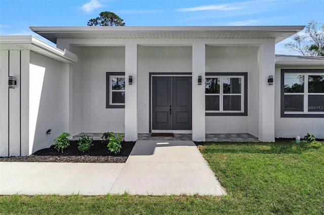 entrance to property with stucco siding and a yard