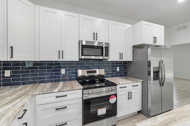 kitchen with light stone counters, stainless steel appliances, backsplash, and visible vents