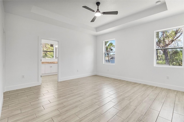 empty room with a healthy amount of sunlight, baseboards, and a tray ceiling