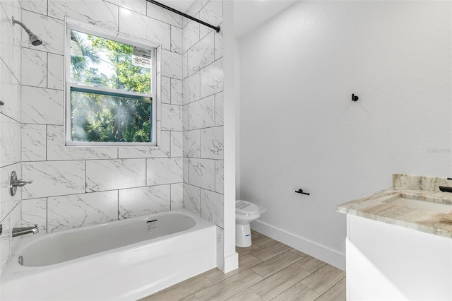 bathroom featuring wood finish floors, toilet, shower / bathing tub combination, baseboards, and vanity