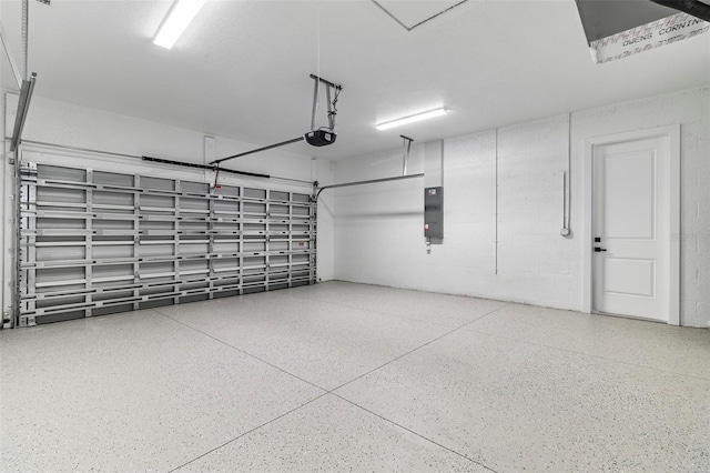 garage with electric panel, a garage door opener, and concrete block wall