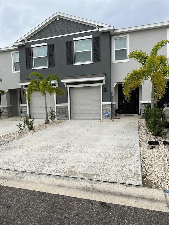 view of front facade with concrete driveway, a garage, stone siding, and stucco siding