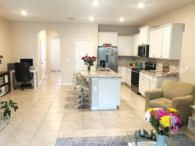 kitchen with visible vents, light stone countertops, light tile patterned flooring, arched walkways, and stainless steel appliances