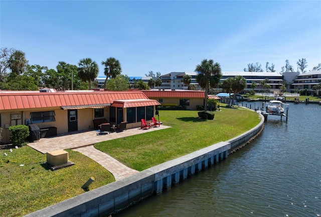 exterior space with a patio area, a lawn, and a water view