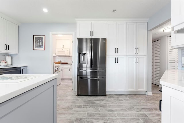 kitchen featuring tasteful backsplash, white microwave, white cabinets, and stainless steel refrigerator with ice dispenser