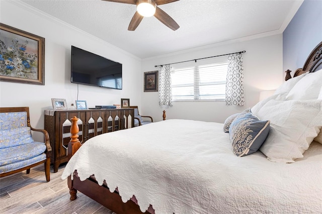 bedroom with ceiling fan, a textured ceiling, wood finished floors, and crown molding