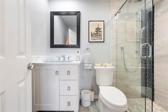 bathroom with baseboards, vanity, a shower stall, and toilet