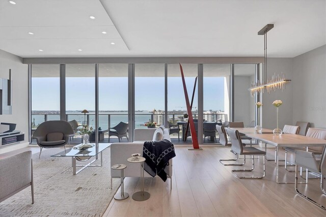 living area with a wall of windows, a wealth of natural light, wood finished floors, and recessed lighting